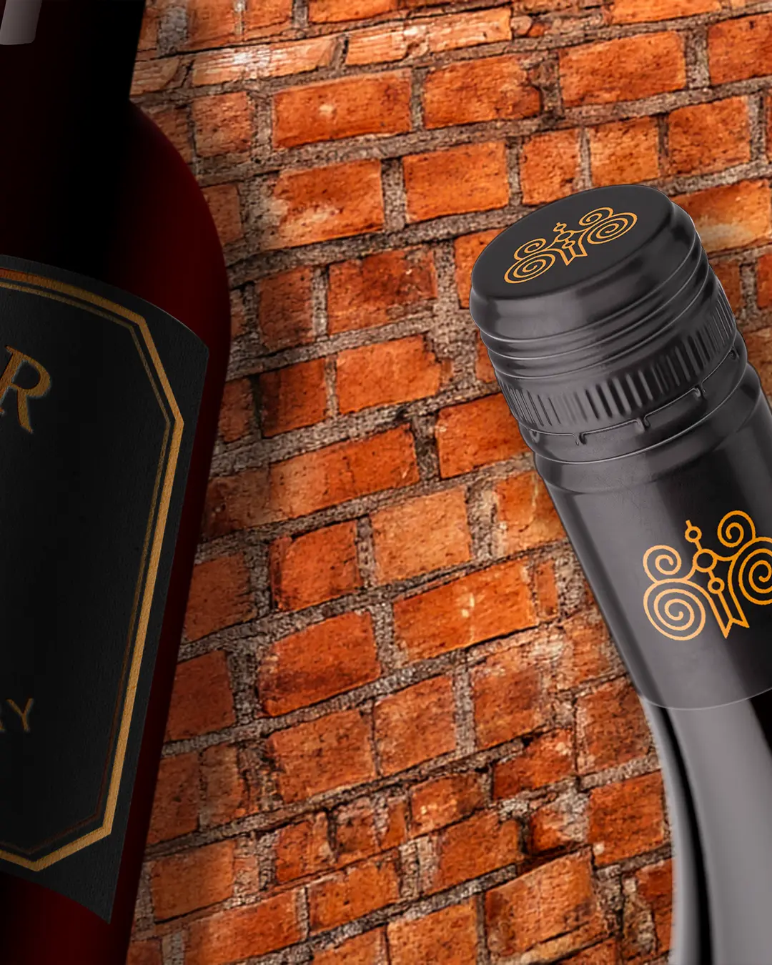 Due bottiglie di vino sono ritratte da vicino davanti a un muro di mattoni rossi; una mostra parte dell'etichetta e l'altra presenta un motivo decorativo dorato sul tappo nero.